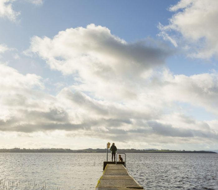 Woman and dog on pier in Portumna, looking out over Lough Derg.